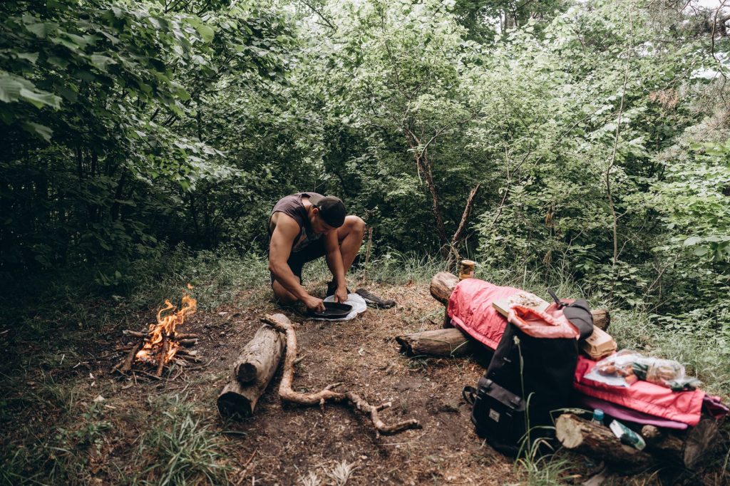 Feu de camp en cours de préparation en forêt avec le matériel de bushcraft étalé au sol