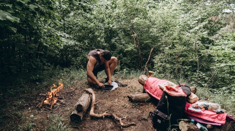 Feu de camp en cours de préparation en forêt avec le matériel de bushcraft étalé au sol